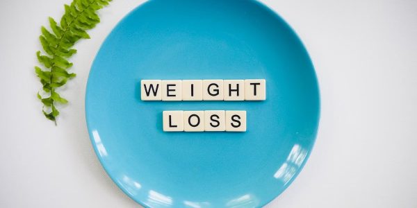 A blue plate with 'weight loss' tiles and a fern leaf on white background.